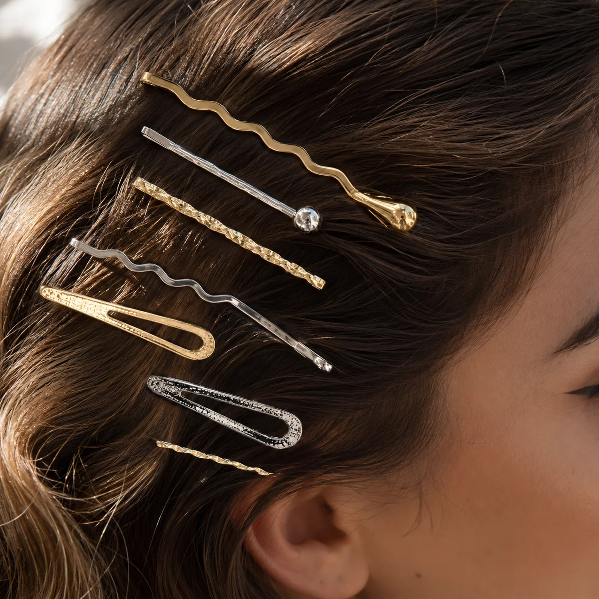 Gold and silver hair clips and pins styled into wavy hair, close-up beauty shot