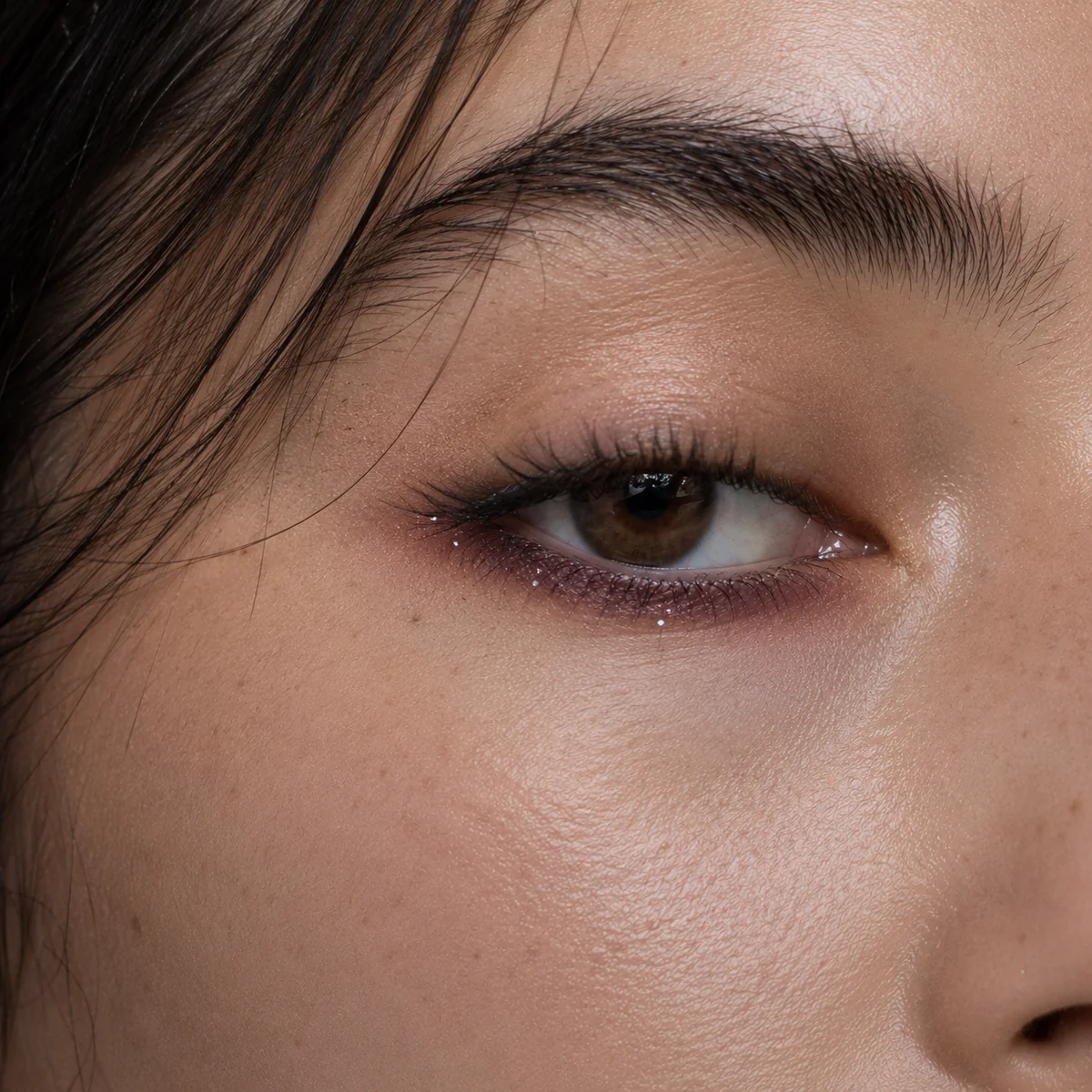 Soft daytime version of glitchy glam makeup with a single smudged line and minimal glitter