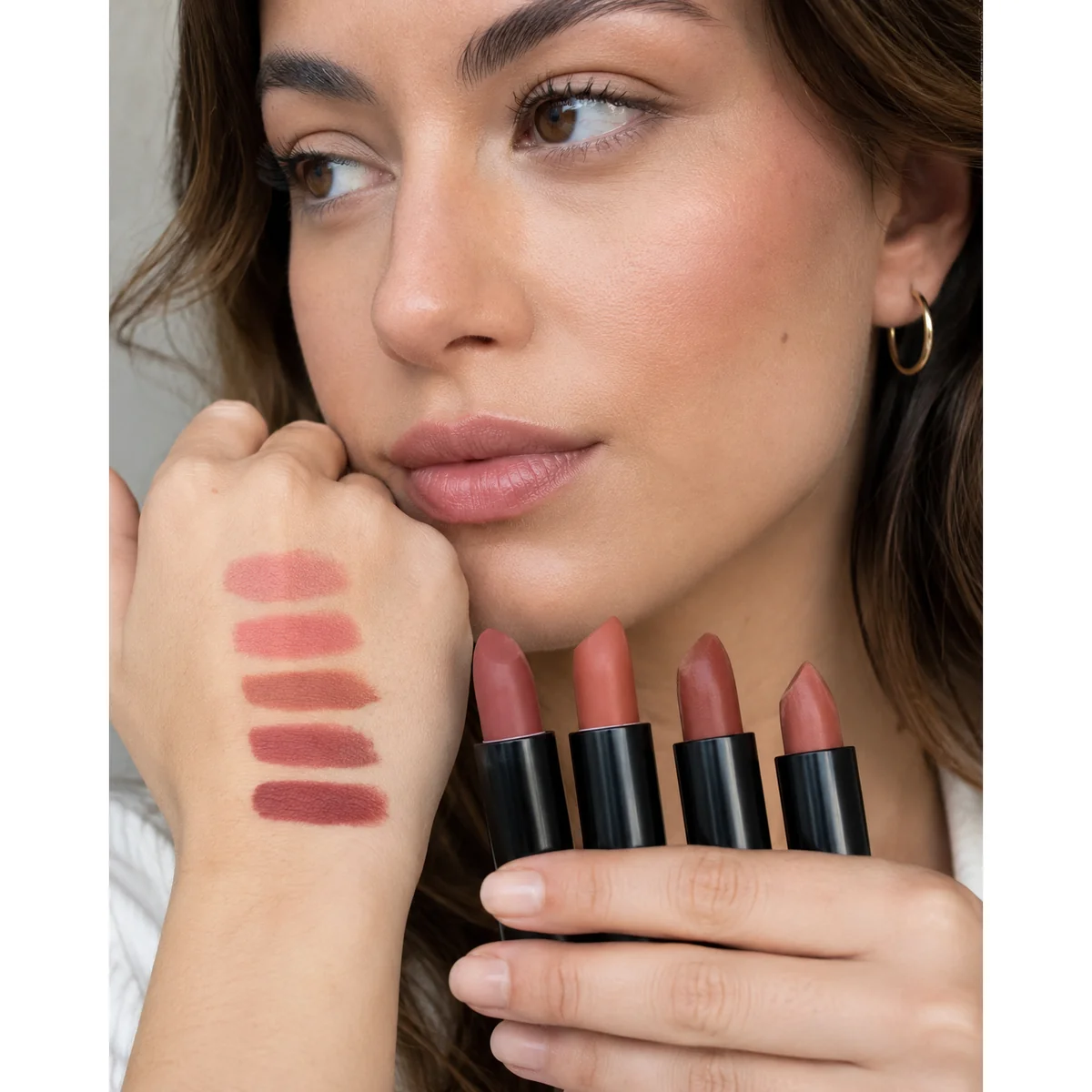 Woman holding several lipstick shades near her lips to compare which one suits her coloring