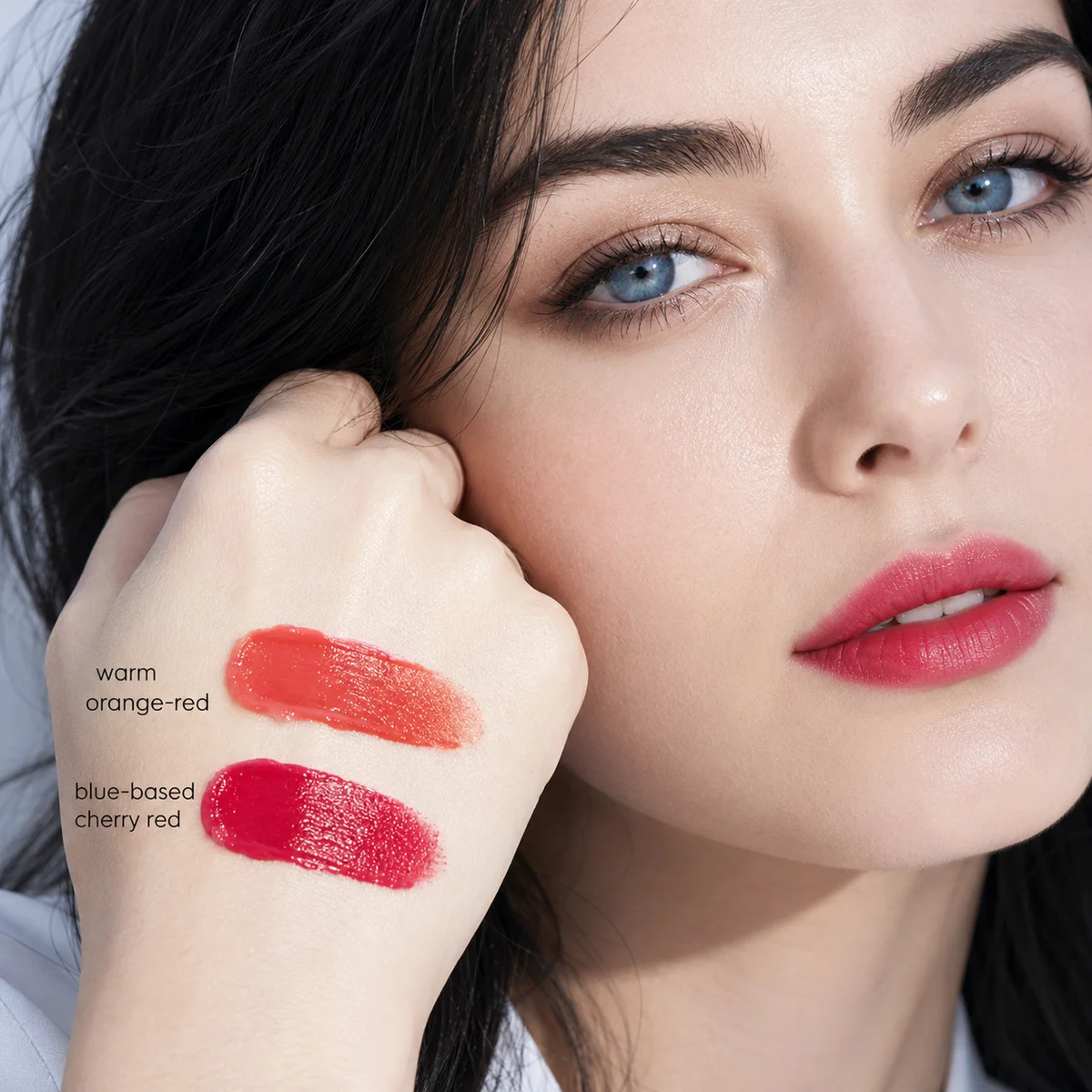 Close-up comparing a warm orange-red swatch and a cool cherry-red swatch against cool winter skin